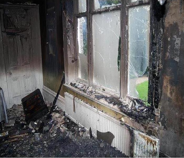 Window and wall damaged with fire, covered in soot and smoke. 
